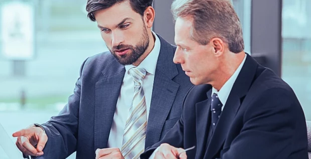 Lawyers discussing while looking and pointing at the laptop in the office.