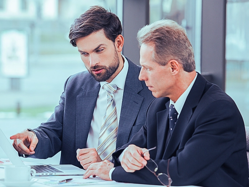 Lawyers discussing while looking and pointing at the laptop in the office.